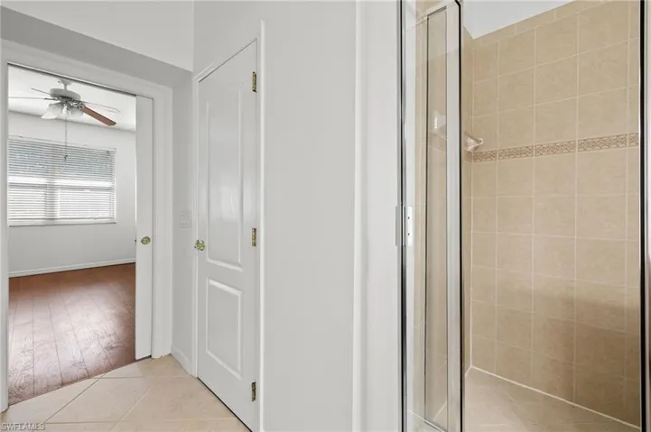 Bathroom featuring a stall shower, light tile patterned flooring, and a ceiling fan