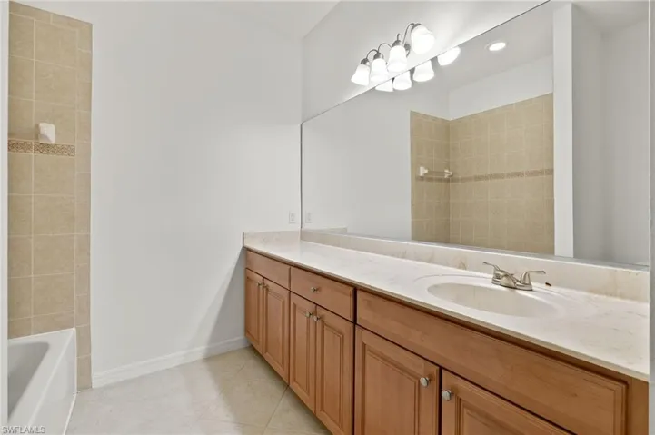 Bathroom with vanity, light tile patterned floors, and  shower combination