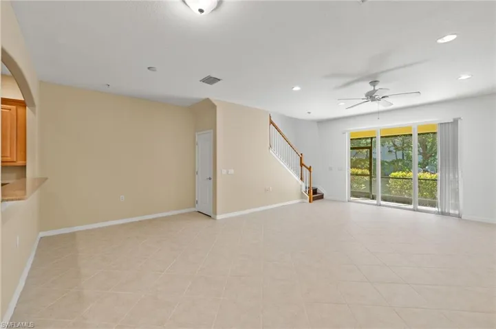 Unfurnished living room featuring stairway, a ceiling fan, recessed lighting, arched walkways, and light tile patterned floors