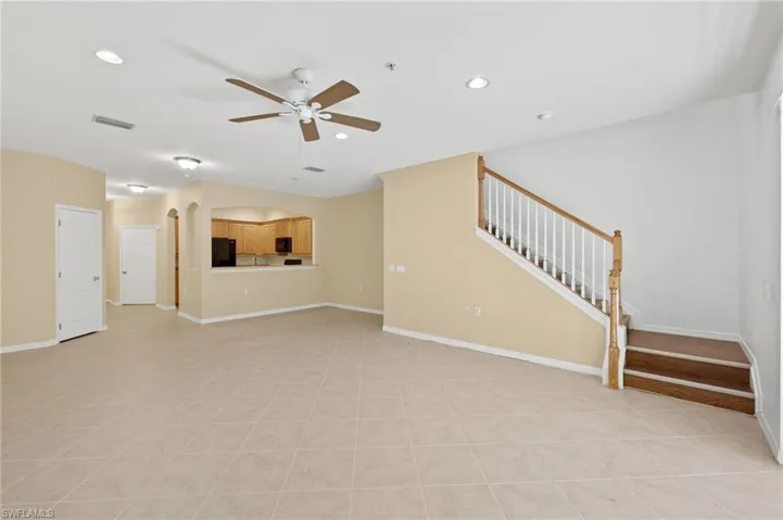 Unfurnished living room with stairway, arched walkways, light tile patterned floors, recessed lighting, and ceiling fan