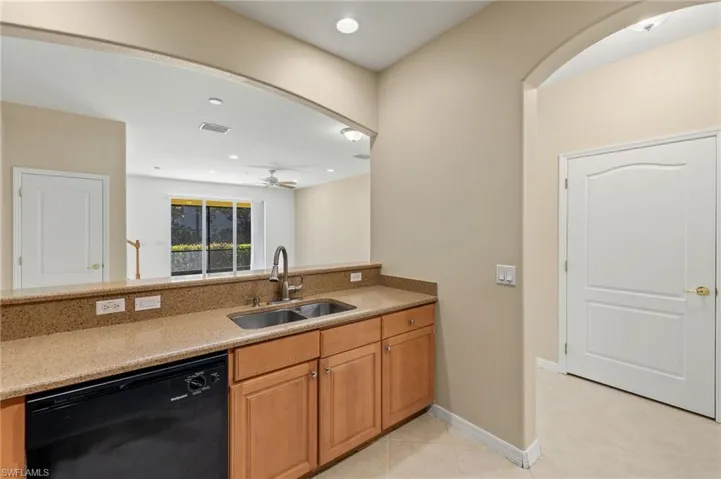 Kitchen featuring light stone counters, black dishwasher, recessed lighting, brown cabinets, and a ceiling fan