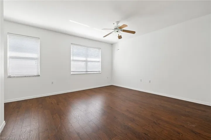 Empty room featuring dark wood-style flooring and a ceiling fan