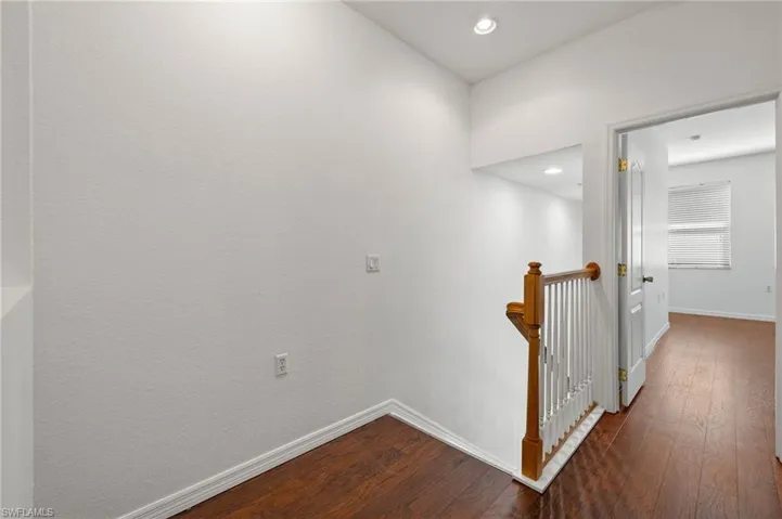 Hall with dark wood finished floors, an upstairs landing, and recessed lighting