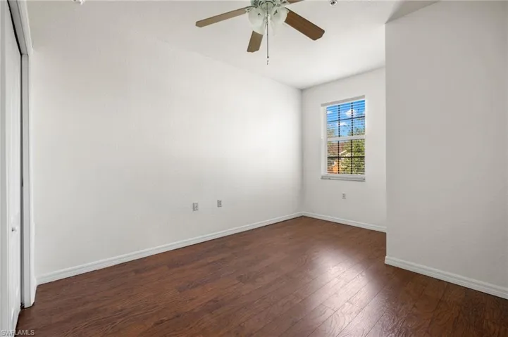 Empty room featuring dark wood-type flooring and a ceiling fan