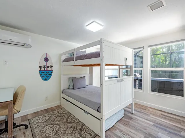 Bedroom featuring light wood-style floors, a wall mounted air conditioner, and a desk