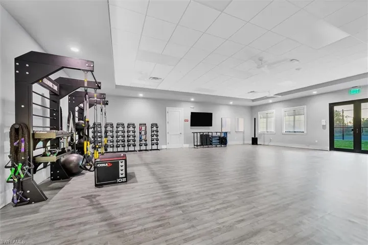 Workout room with a tray ceiling and light hardwood / wood-style floors