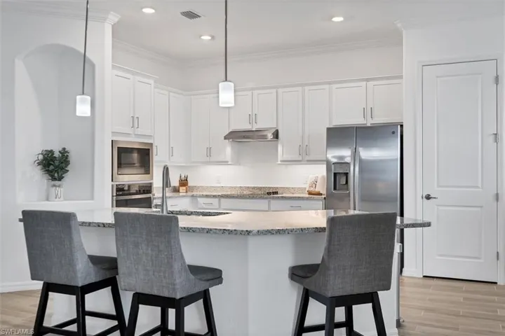 Kitchen with appliances with stainless steel finishes, sink, a breakfast bar area, and white cabinets