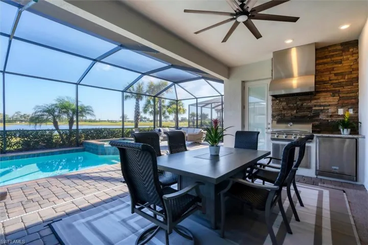 View of swimming pool featuring a water view, area for grilling, glass enclosure, and a patio