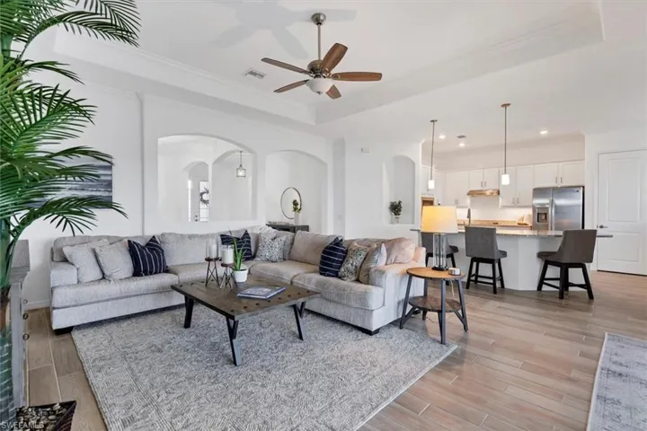 Living room featuring crown molding, a tray ceiling, light hardwood / wood-style flooring, and ceiling fan