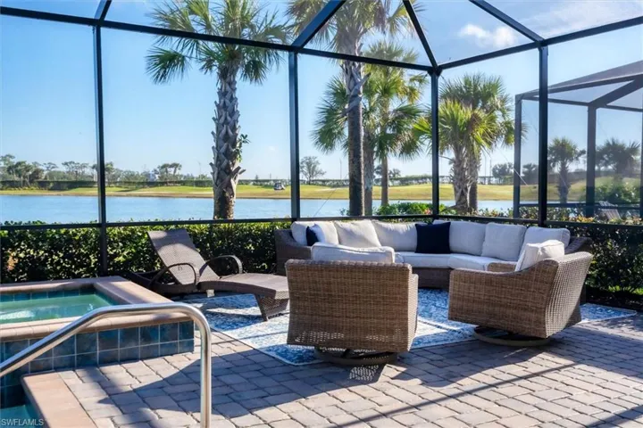 View of patio with a jacuzzi, a lanai, outdoor lounge area, and a water view