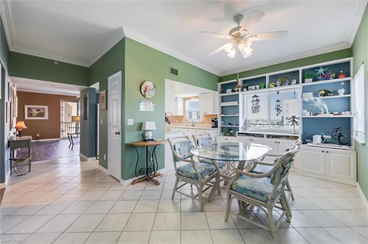 Dining room with ornamental molding, light tile patterned flooring, and ceiling fan