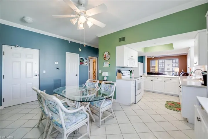 Dining area featuring crown molding, light tile patterned flooring, and a ceiling fan