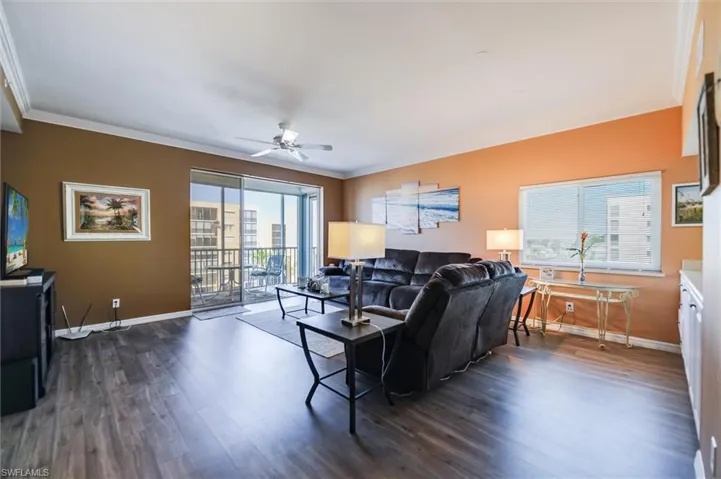 Living room featuring ornamental molding, dark wood-style floors, and ceiling fan