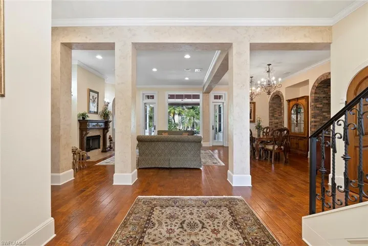 Foyer with stairs, dark wood-style flooring, a fireplace, crown molding, and recessed lighting
