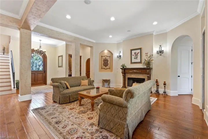 Living area featuring ornamental molding, arched walkways, hardwood / wood-style floors, a fireplace, and stairs