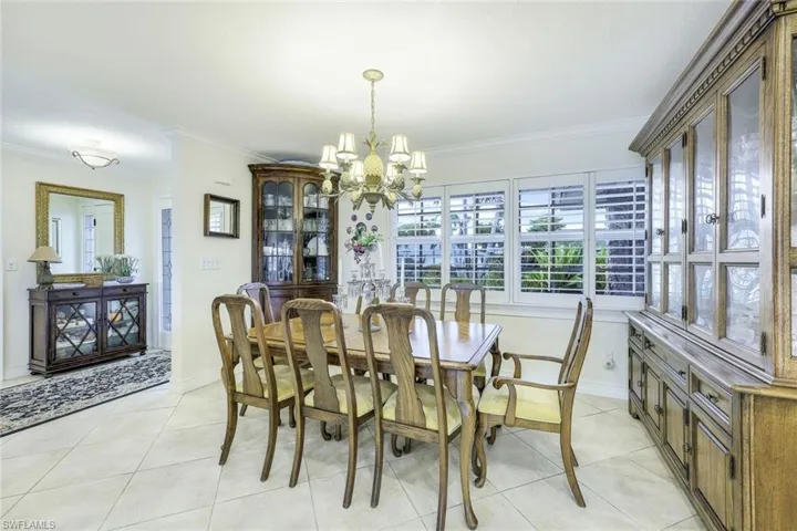 Dining area with Foyer to the left. So many extras here . . . plantation shutters, crown molding, and large neutral tile on the diagonal. Lots of natural light throughout this much-loved home!