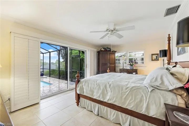 Primary Bedroom also looks out to the pool and extensive water view! Note the plantation shutters and crown molding.