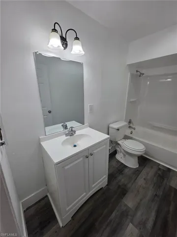Full bath featuring vanity, shower / bathtub combination, and dark wood-style floors