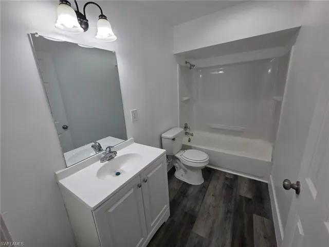 Full bath with vanity,  shower combination, and dark wood-style flooring
