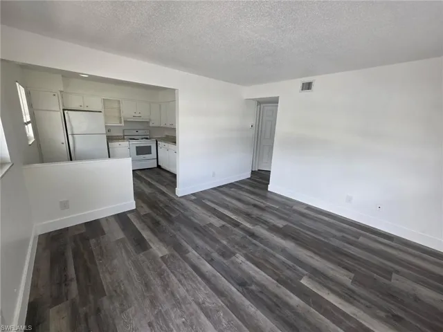 Unfurnished living room with a textured ceiling and dark wood-style floors