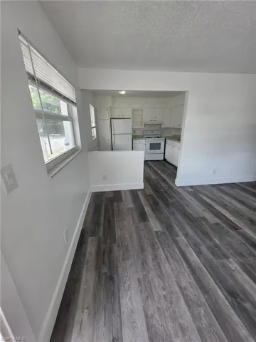 Unfurnished living room with dark wood-type flooring and a textured ceiling