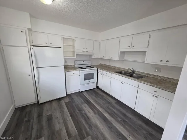 Kitchen featuring white appliances, white cabinetry, a textured ceiling, open shelves, and dark wood finished floors