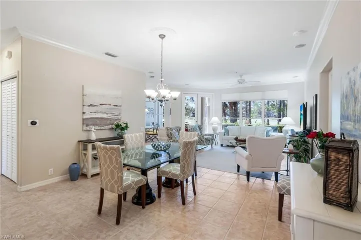 Dining room with ornamental molding, a ceiling fan, a chandelier, and light tile patterned floors