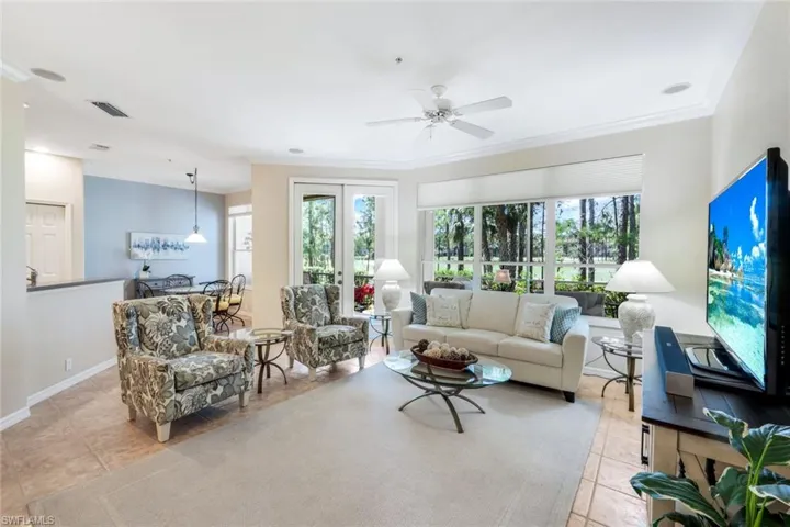 Living area featuring ornamental molding, healthy amount of natural light, light tile patterned floors, and a ceiling fan
