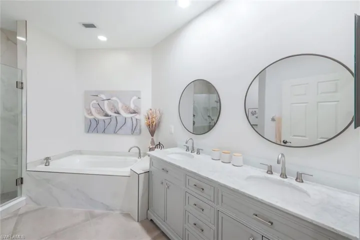Bathroom with a garden tub, a marble finish shower, double vanity, light tile patterned flooring, and recessed lighting