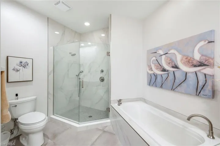 Bathroom with a marble finish shower, a garden tub, light tile patterned flooring, and recessed lighting