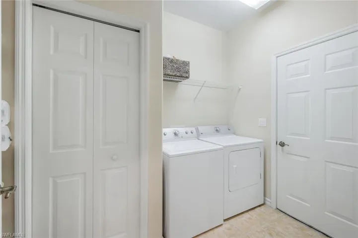 Laundry room with independent washer and dryer and light tile patterned floors