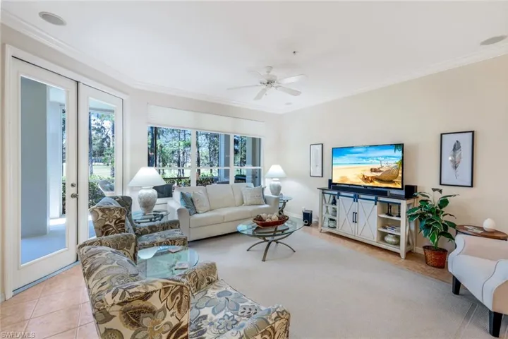 Living area with ornamental molding, light tile patterned flooring, healthy amount of natural light, and a ceiling fan
