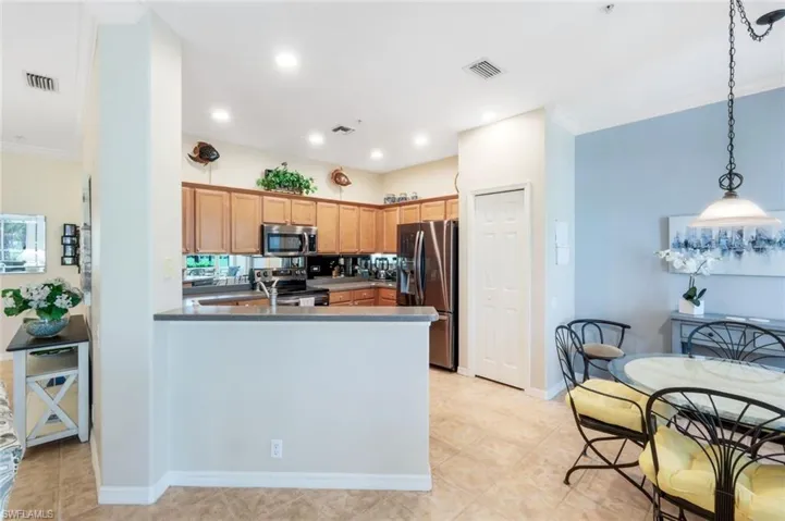Kitchen featuring crown molding, stainless steel appliances, hanging light fixtures, a peninsula, and recessed lighting