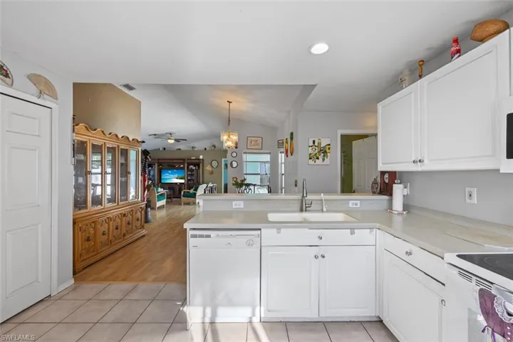 Kitchen with visible vents, a sink, white appliances, a peninsula, and ceiling fan