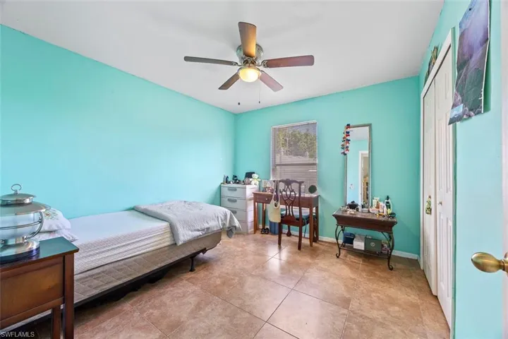 Bedroom featuring light tile patterned floors, ceiling fan, and baseboards