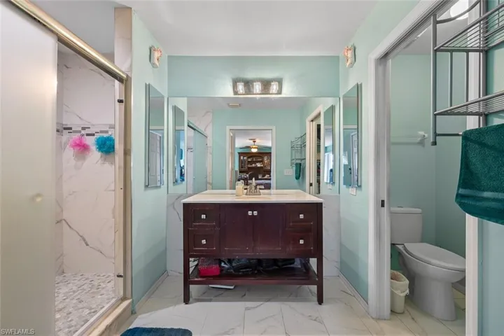 Full bathroom featuring a marble finish shower, marble finish floor, toilet, and vanity