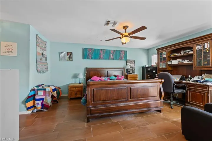 Bedroom featuring ceiling fan, baseboards, visible vents, and built in study area