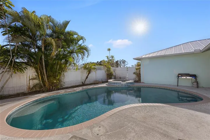 View of swimming pool featuring a patio, a fenced backyard, and a pool with connected hot tub