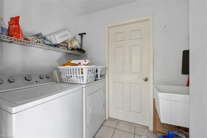 Clothes washing area with laundry area, light tile patterned floors, and separate washer and dryer