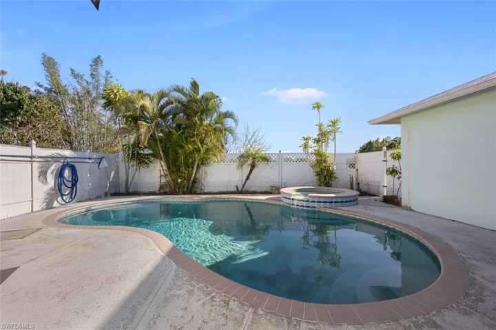 View of swimming pool featuring a pool with connected hot tub, a patio area, and a fenced backyard