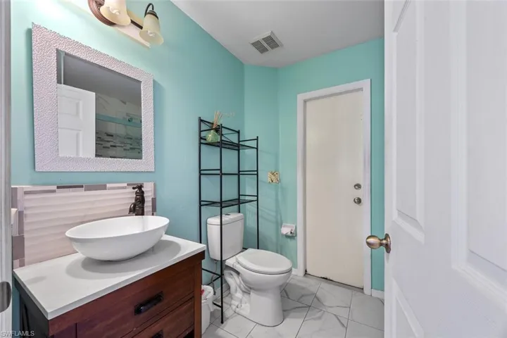 Bathroom with vanity, toilet, visible vents, and marble finish floor