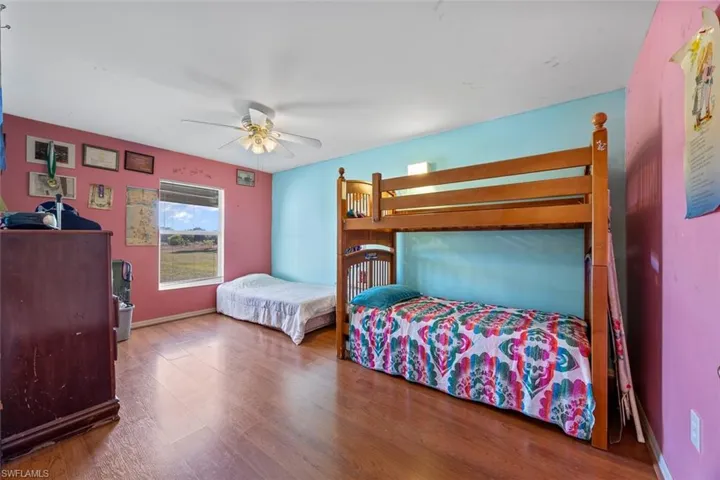 Bedroom with a ceiling fan, wood finished floors, and baseboards