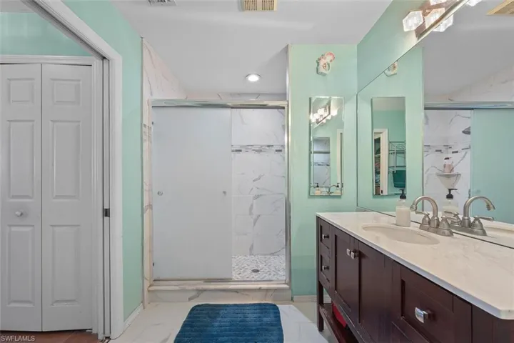 Full bathroom with visible vents, marble finish floor, a stall shower, and vanity