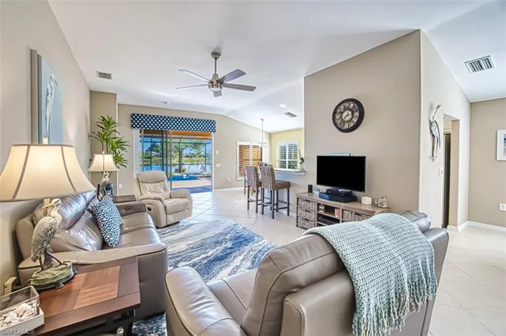Tiled living room featuring ceiling fan and vaulted ceiling