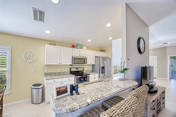 Kitchen with a kitchen bar, appliances with stainless steel finishes, sink, white cabinets, and light tile patterned flooring