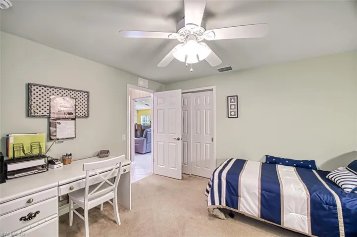 Carpeted bedroom with ceiling fan and a closet