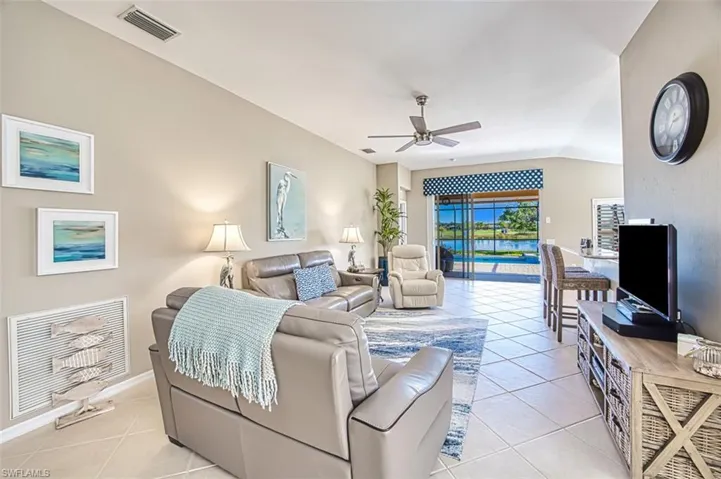 Living room featuring ceiling fan, light tile patterned floors, and lofted ceiling