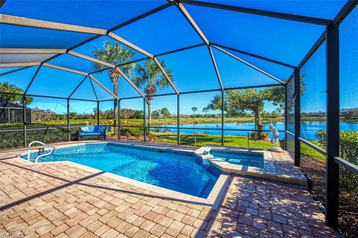 View of pool featuring a lanai, a patio area, an in ground hot tub, and a water view