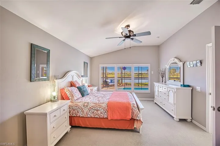 Carpeted bedroom featuring ceiling fan and lofted ceiling