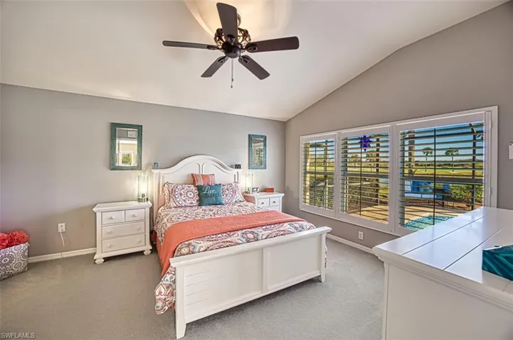 Carpeted bedroom featuring vaulted ceiling and ceiling fan